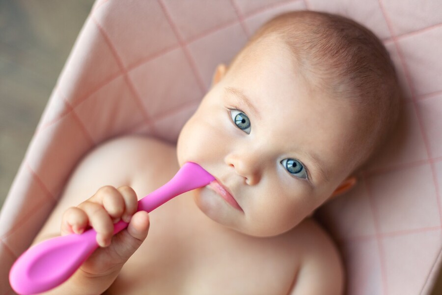 closeup of baby chewing on pink teether